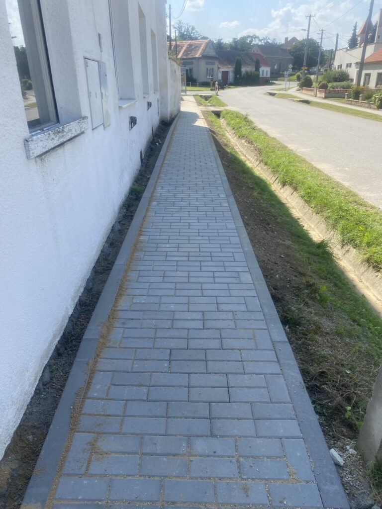 Úzký dlážděný chodník podél domu