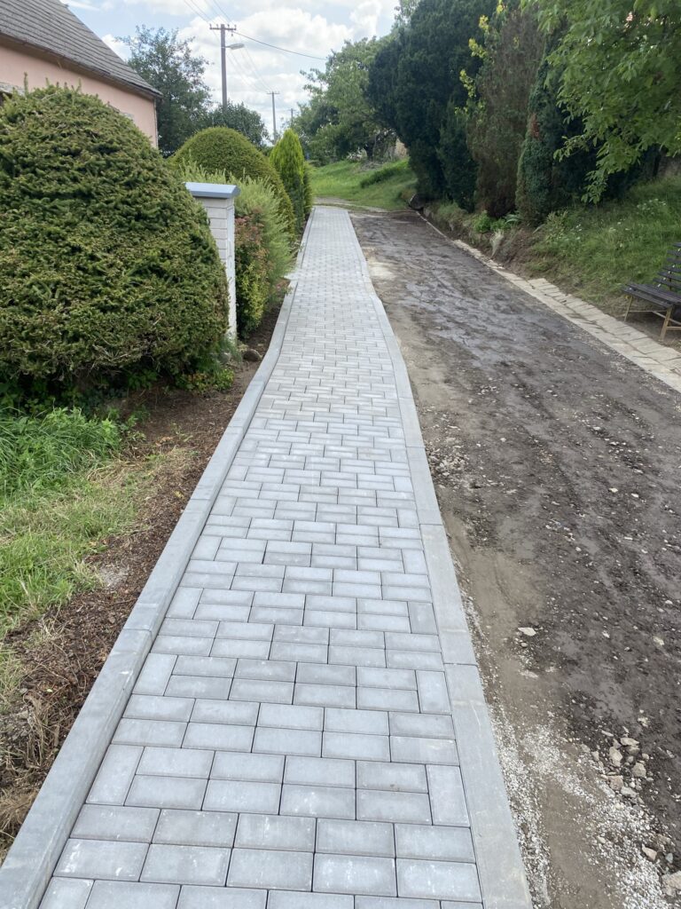 Dlážděný chodník mezi domy a zahradami
