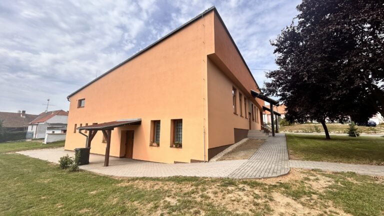 Boční pohled na oranžovou budovu a dlážděnou plochu
