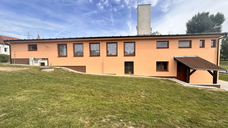 Oranžová fasáda budovy směrem k travnaté ploše