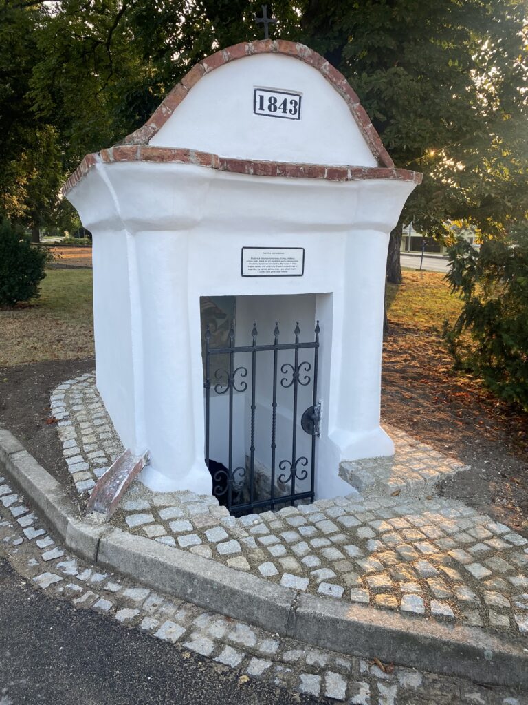 Malá kaple se vstupní mříží a okolní dlažbou