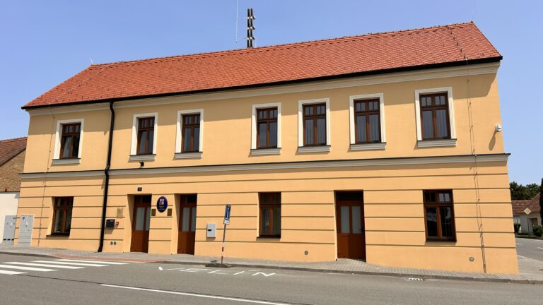 Čelní pohled na žlutou fasádu a vstupy do budovy