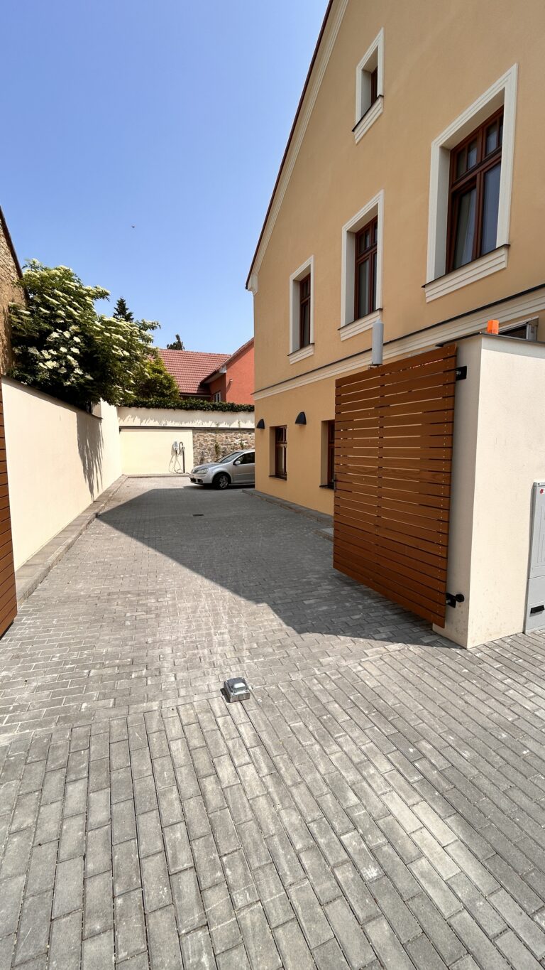 Boční vstup do žluté budovy a dlážděná cesta